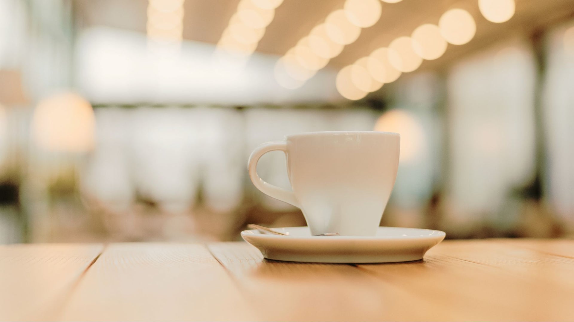 White coffee cup and saucer on a wooden table with a blurred background