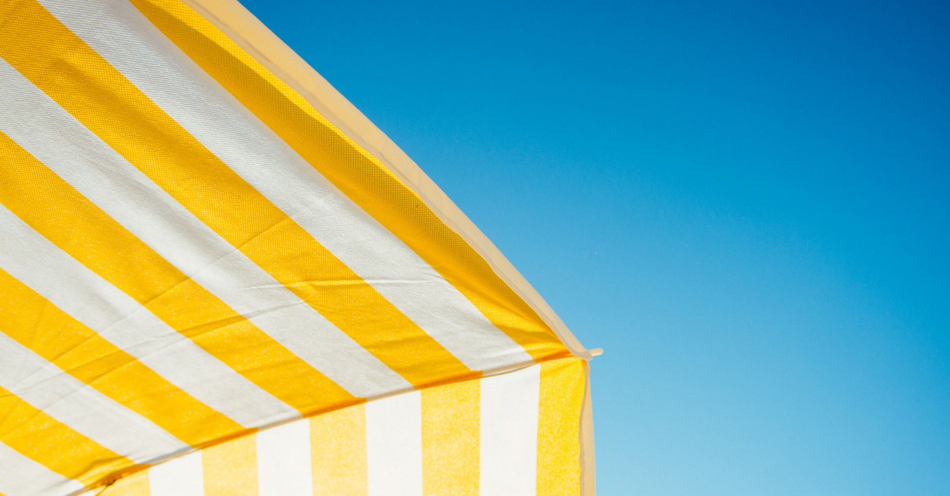 Yellow and white striped canopy against a clear blue sky